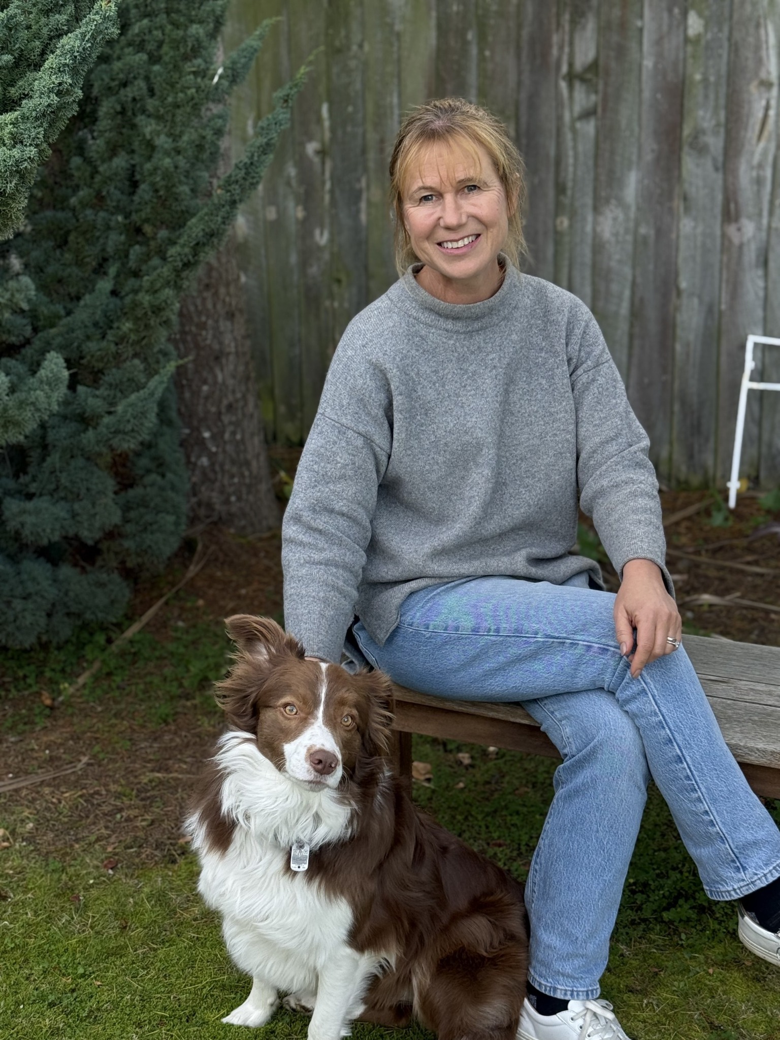 Sarah seated outdoors with her dog